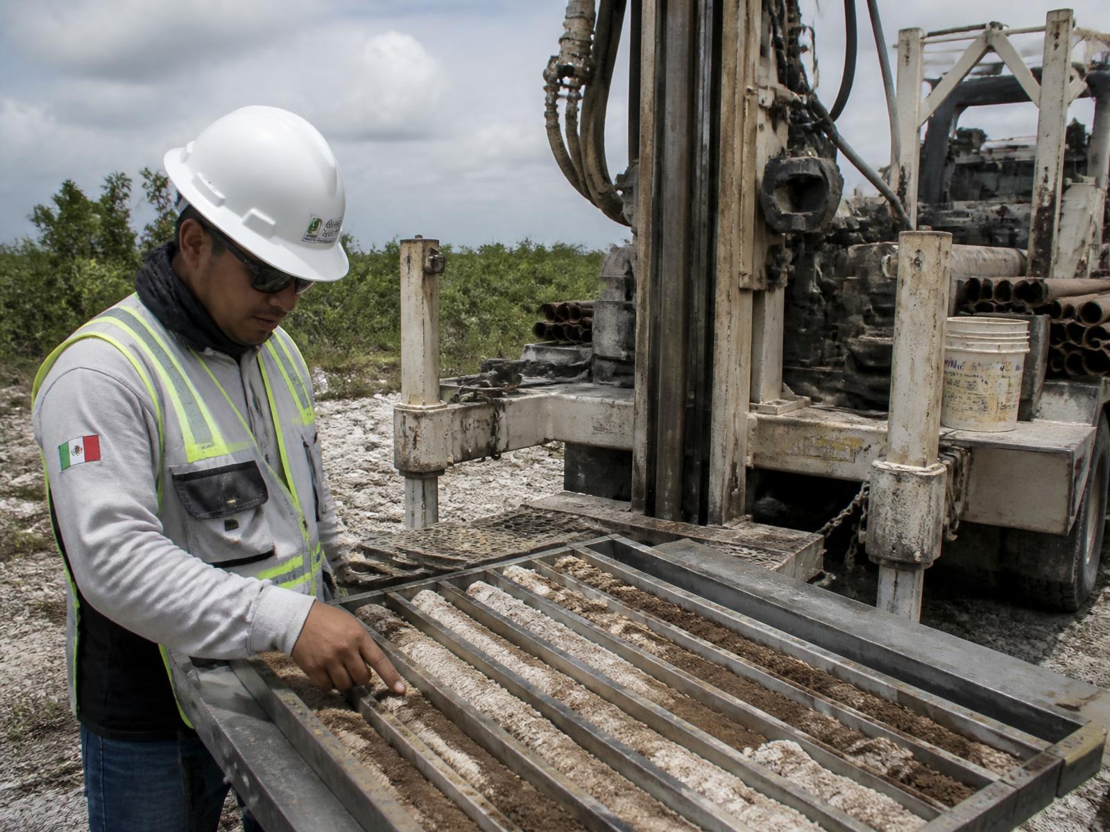 Técnico de AvanceMP revisando un testigo de roca caliza junto a un equipo de sondeo exploratorio en Yucatán