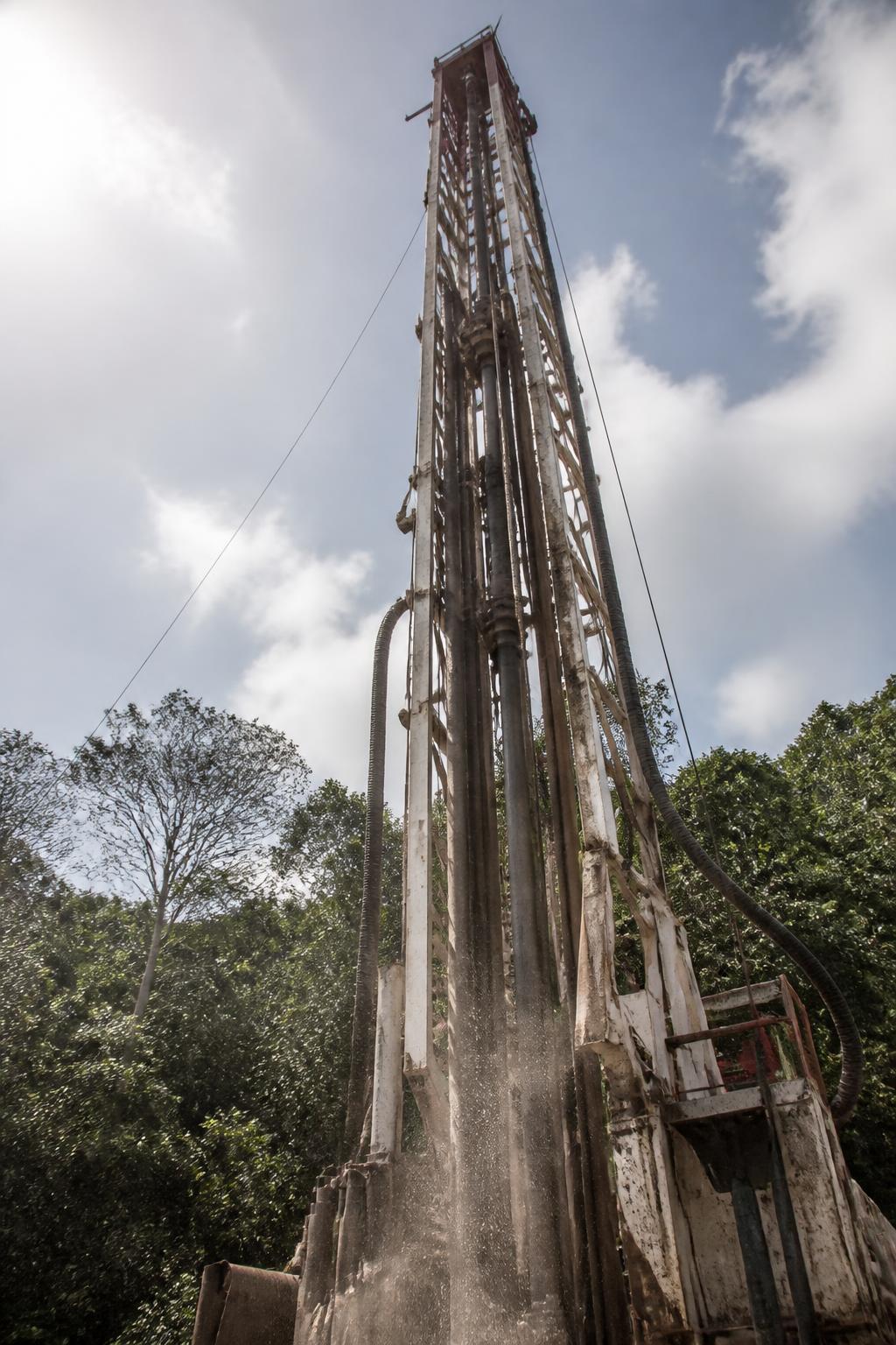 Mástil de un equipo de perforación visto desde abajo, con la selva de la Península de Yucatán al fondo